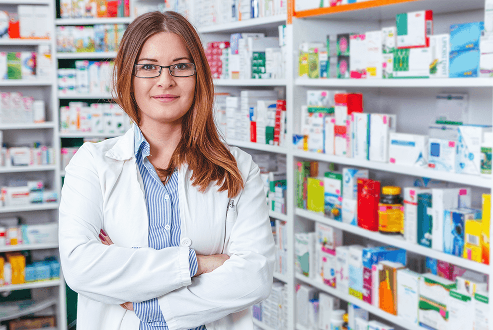 Pharmacist standing in front of shelves of medicine boxes and bottles