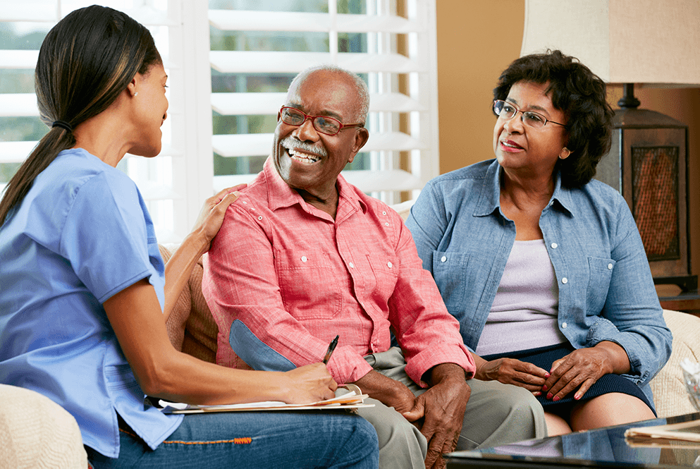 Medical professional talking to older couple in their home