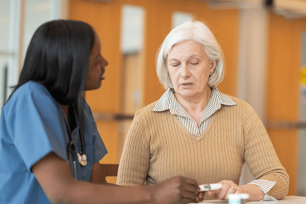 Medical professional talking to older woman at counter